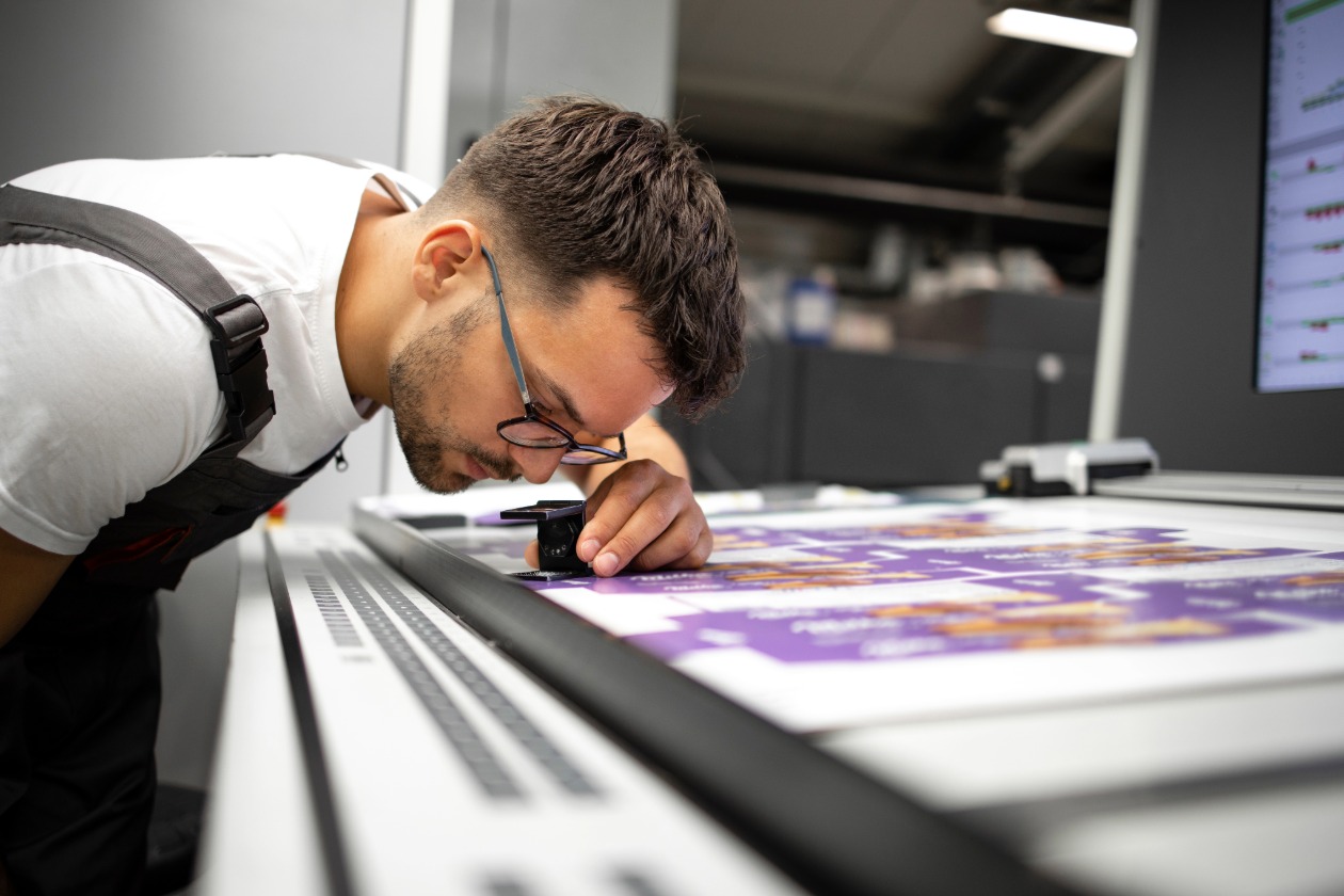 Mitarbeiter prüft Druckqualität eines individuellen Druckprodukts in einer Druckerei